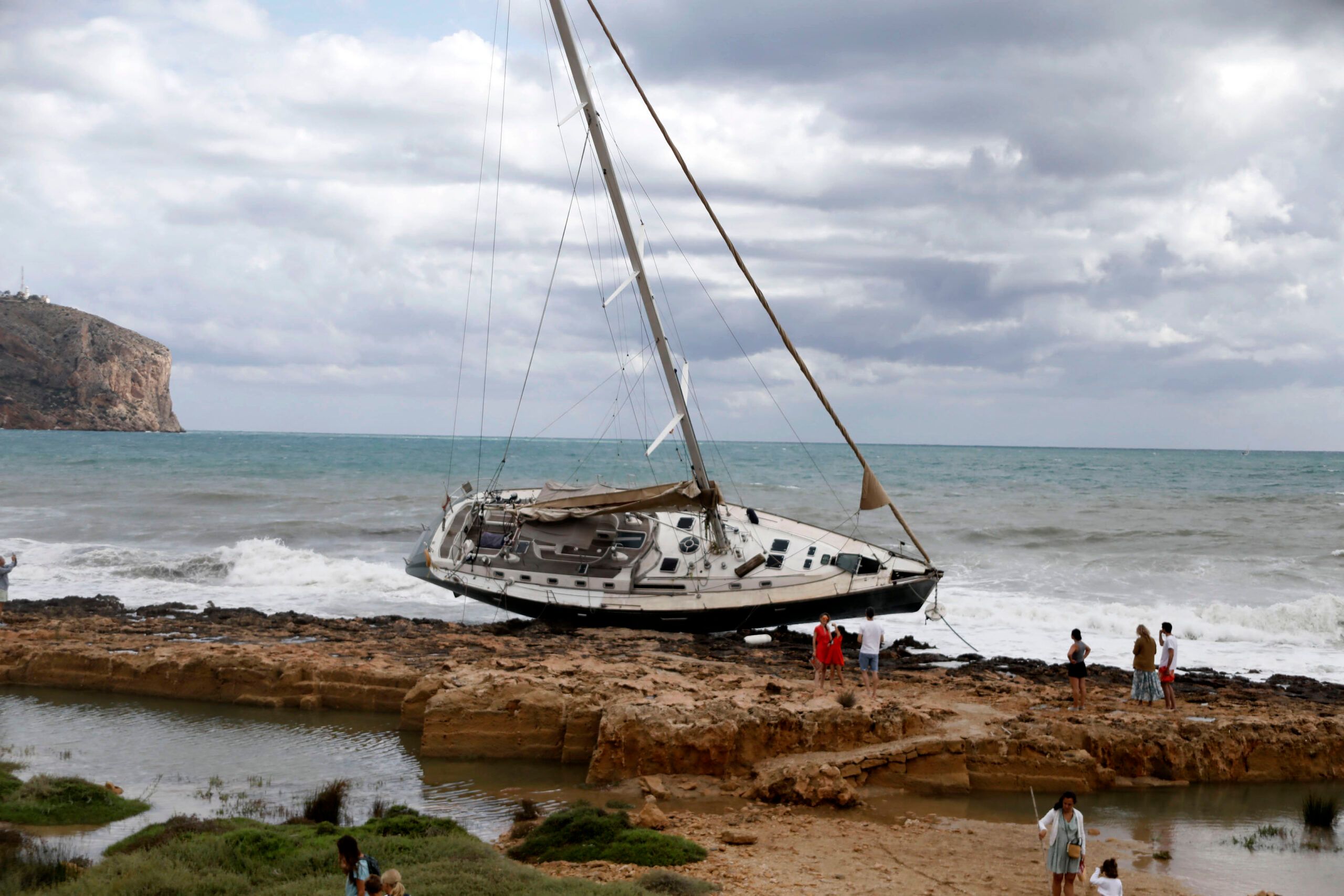 The Bau Bau, a large blue sailboat, grounded on the rocky coastline of the Primer Muntanyar in Jávea